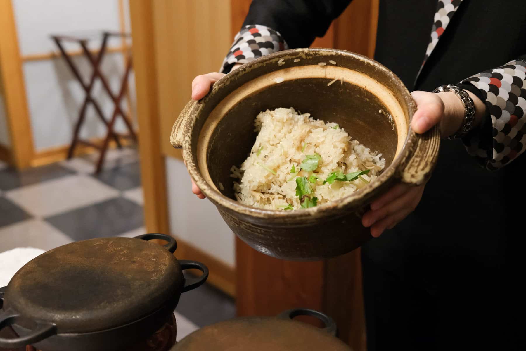 服務員正在端著一鍋裝滿飯的陶製鍋,為客人服務。