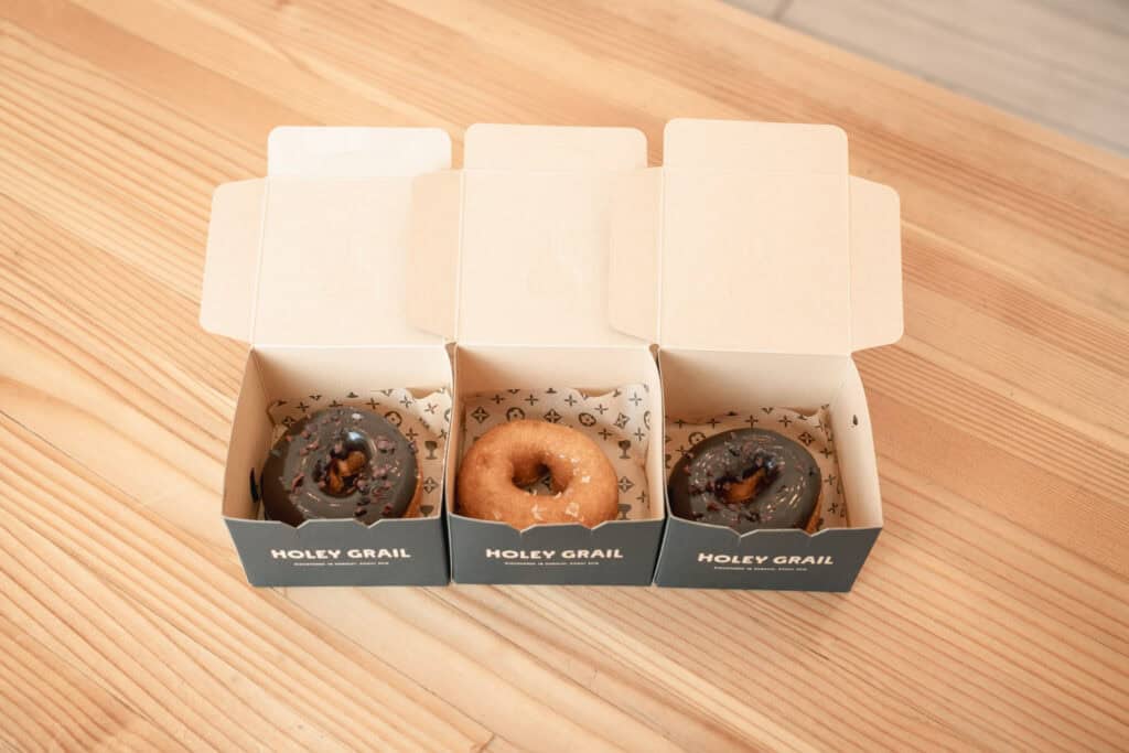 三個 Holey Grail Donuts 的甜甜圈分別裝在印有品牌標誌的紙盒中